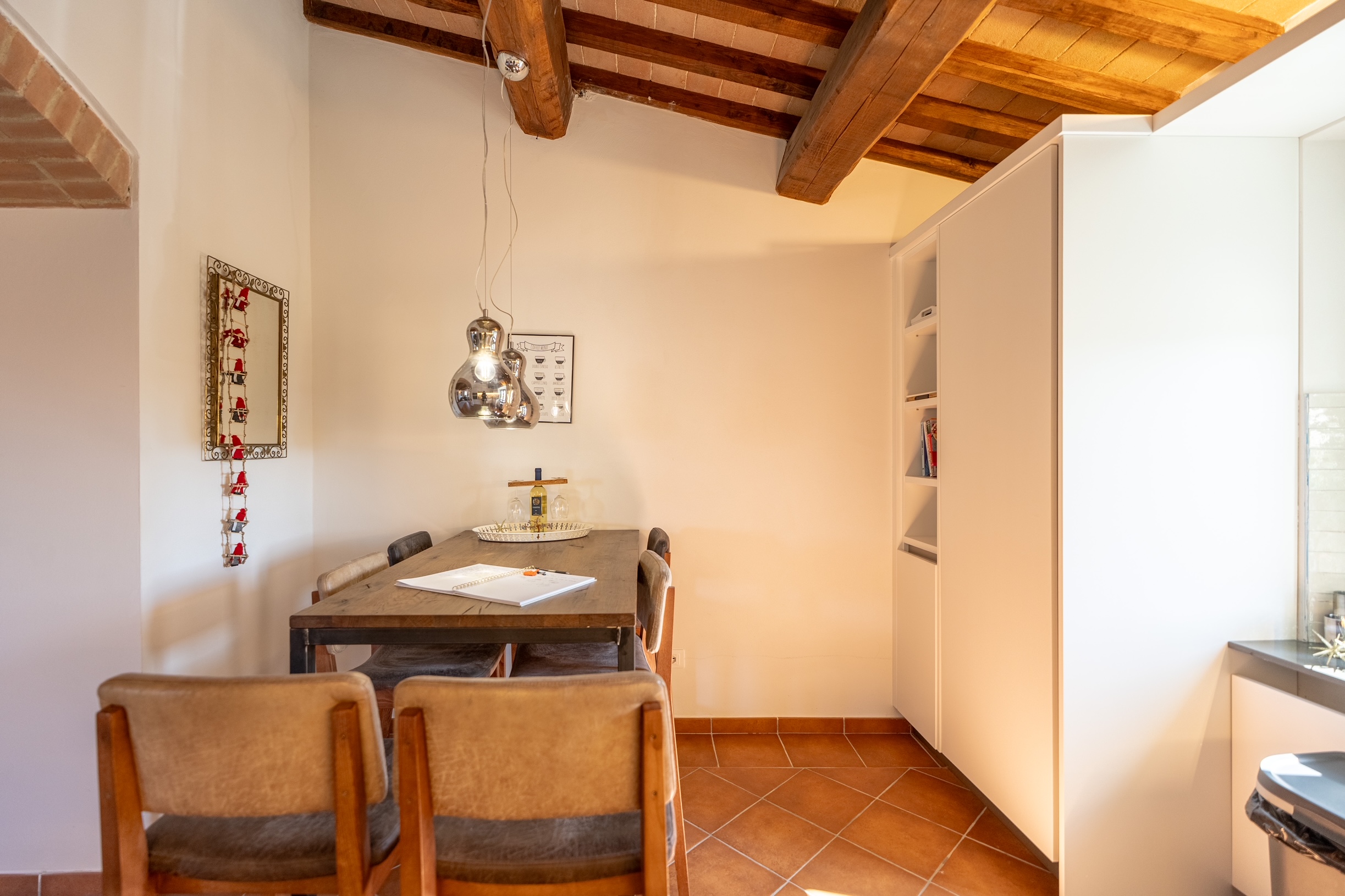 Dining area with timber beams, pendant light and kitchen cabinetry