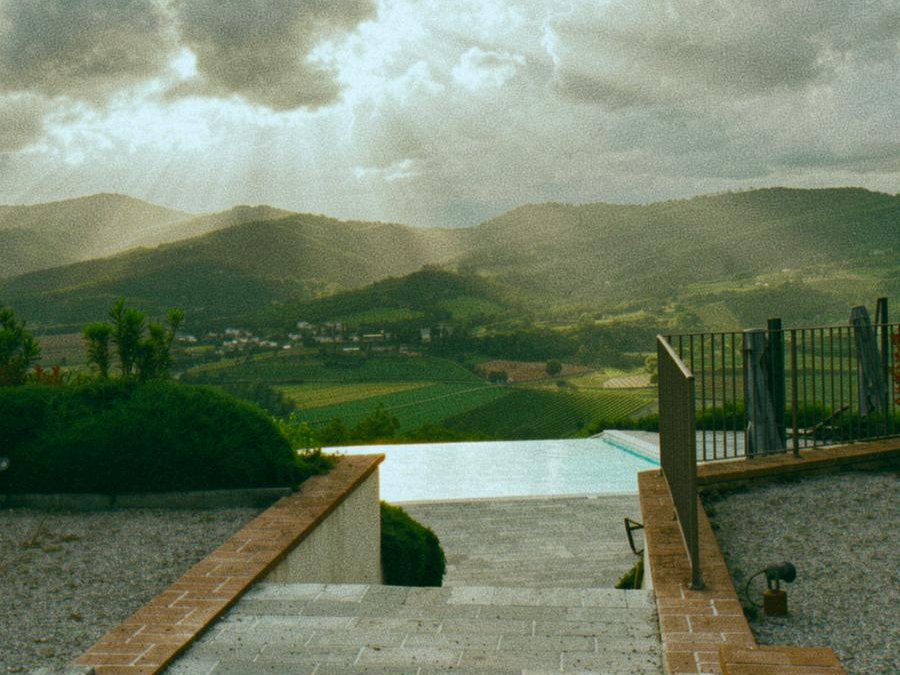 Casa Luna infinity pool terrace at golden hour, looking out across the Niccone Valley toward the Umbrian hills