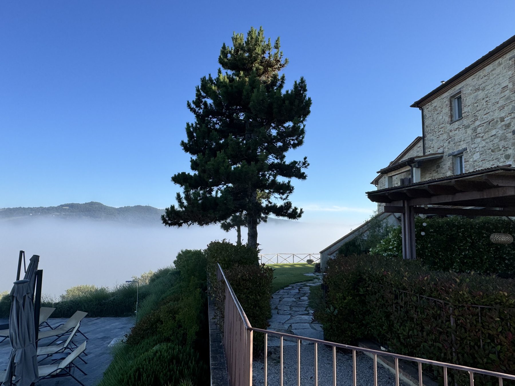 Casa Luna stone villa exterior at dawn with morning mist rolling through the Niccone Valley, Umbria