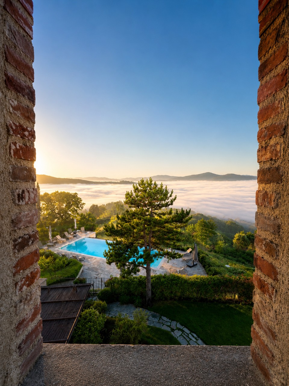 View through stone window to the infinity pool and cloud-filled Niccone Valley at sunrise